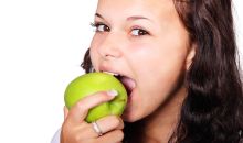 Dívka kouše do jablka